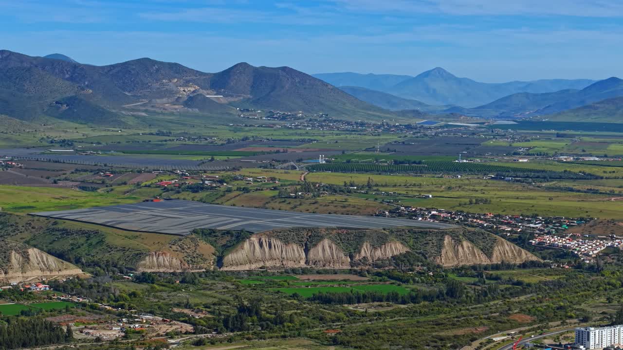Aerial telephoto view of plantations with protective nets in the Limarí Valley with green mountains on a sunny day. Plantations for Chilean pisco