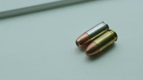 close up pan right of a hollow point and a round nose 9mm bullet angled side by side