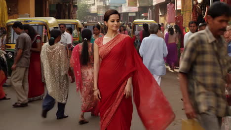 woman in a red sari walking on a busy indian street