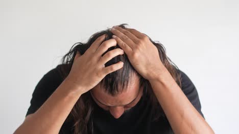 라틴계 남자가 머리카락이 후퇴하고 털이 벗겨져서 머리카락을 확인하고 있습니다.
