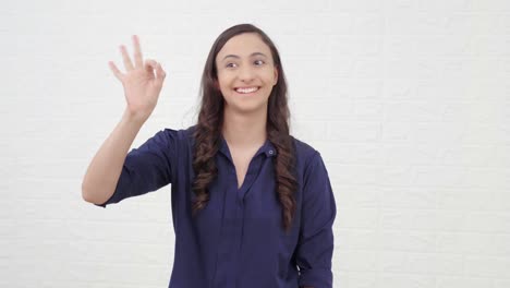 uma rapariga indiana a apreciar alguém com um sinal de "okay"
