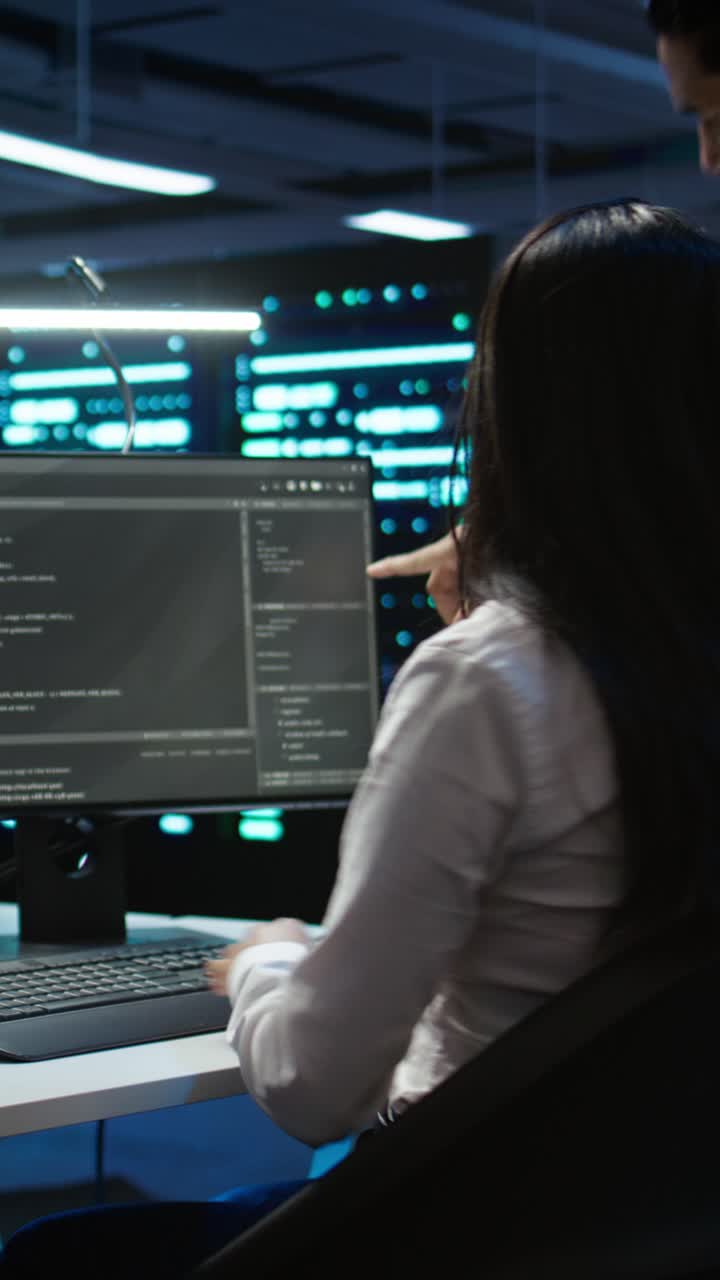 Programmatrice che digita codice in una sala server buia