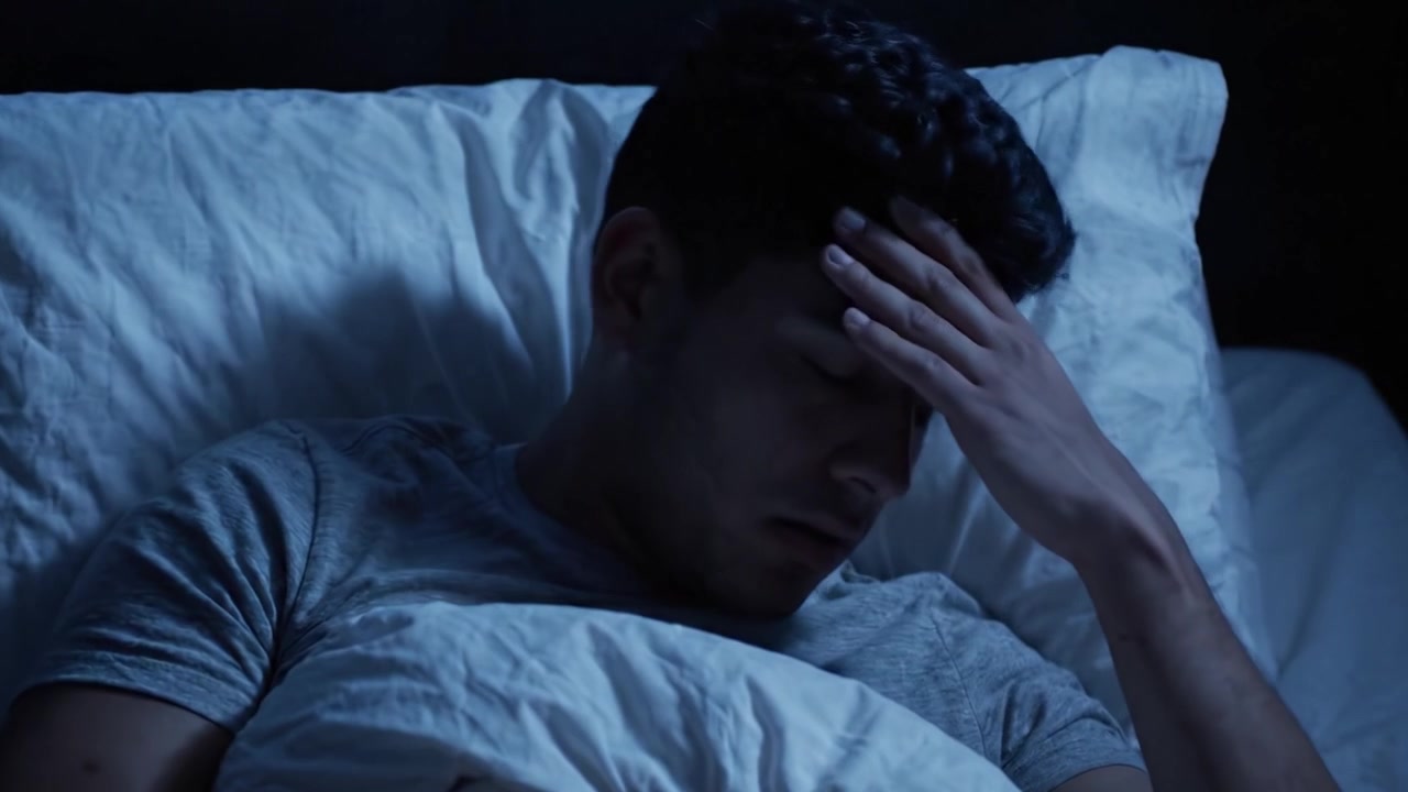 Seorang pemuda beralih dari terjaga gelisah ke tidur nyenyak, menangkap kontras antara insomnia dan kelegaan karena akhirnya bisa tidur di malam hari.