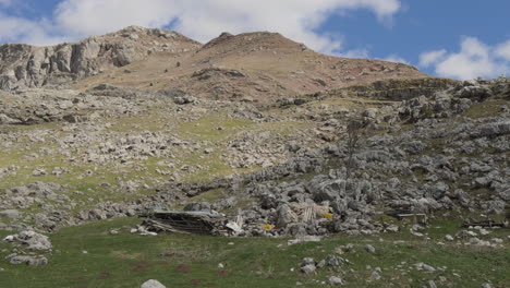 a scenic mountain view captured from a moving car, showcasing a rugged landscape of rocky terrain and low grass-covered fields. sunny day, slow motion