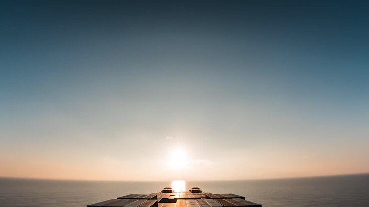 Timelapse or hyperlapse of a sea large cargo container ship sailing through the ocean sea water during night and day time while sun sets and rises multiple times. Colorful cargo containers visible.