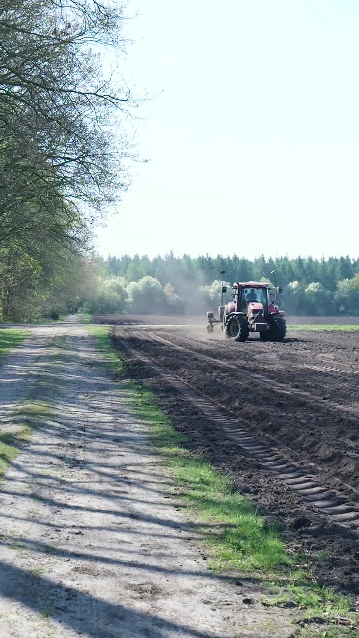 Trattore rosso che semina in un campo agricolo rurale