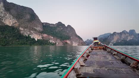 Un-Pequeño-Barco-Se-Desliza-Por-Las-Aguas-De-Un-Lago-En-El-Parque-Nacional-De-Khao-Sok,-Surat-Thani,-Tailandia