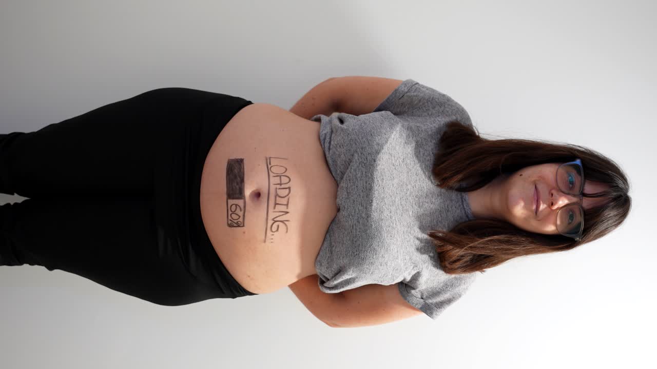 Mulher grávida exibindo um anúncio criativo de barra de progresso da gravidez na sua barriga.