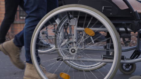 camera focuses on wheel of a wheelchair spinning on a walk in the street