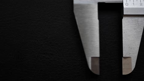 close-up of a metal caliper on a dark background