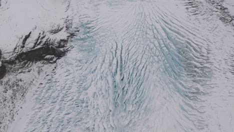 aerial view over ice cracks and formations in virkisjokull glacier covered in snow, iceland