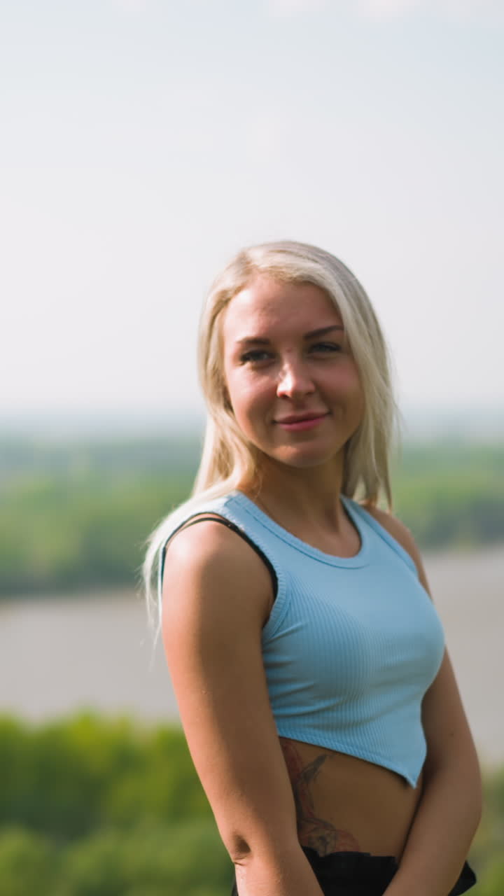 Pretty woman turns head and smiles to beloved man motorcyclist at romantic date on hilly bank of large river on sunny spring day slow motion