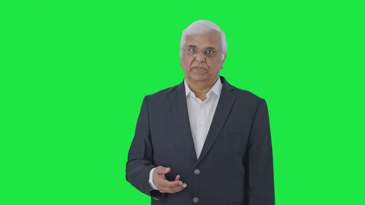 고위 인디언 저널리스트가 녹색 스크린에서 뉴스를 읽고 있습니다.