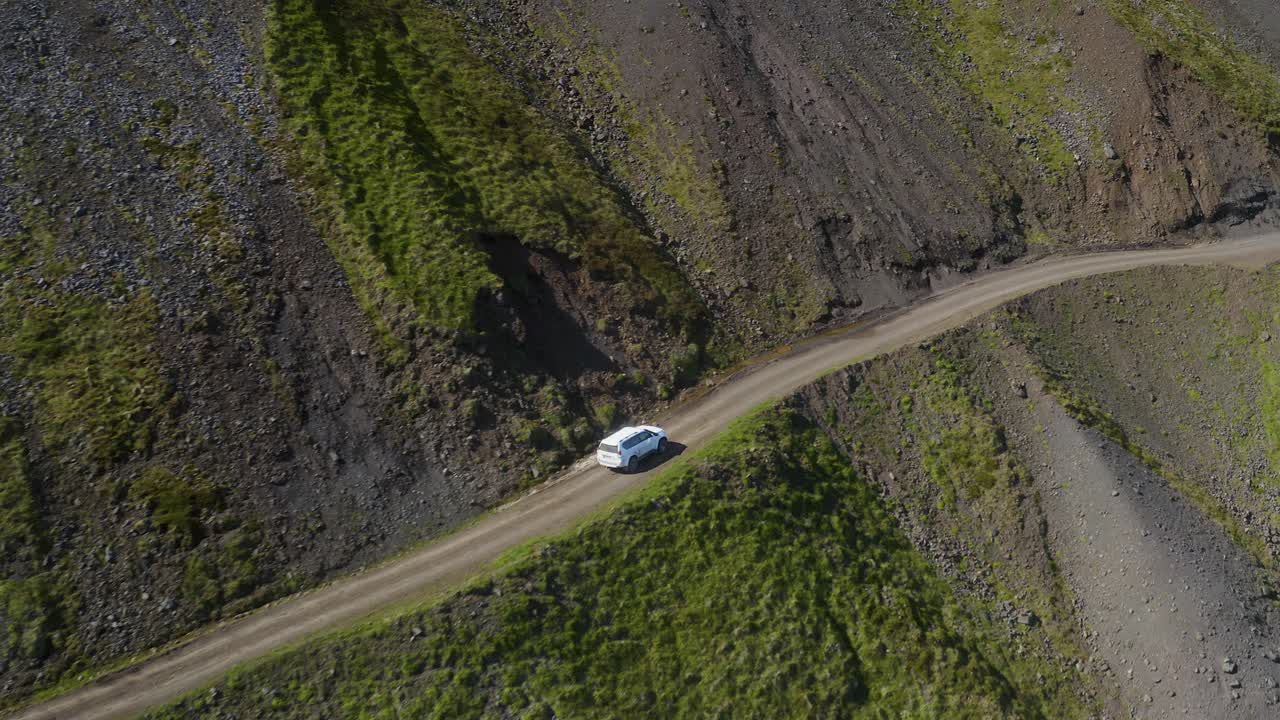 Ripresa aerea in movimento di un'auto su strada di montagna durante una giornata di sole - Svalvogavegur, Europa
