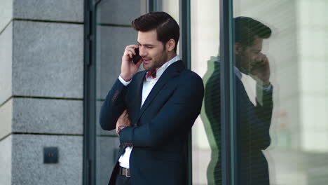 Closeup-businessman-standing-at-street.-Man-smiling-during-phone-talk-at-street