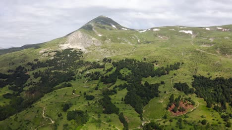 gran tiro de carro de drones hacia atrás de las grandes montañas verdes de sharr en el norte de macedonia en un día nublado