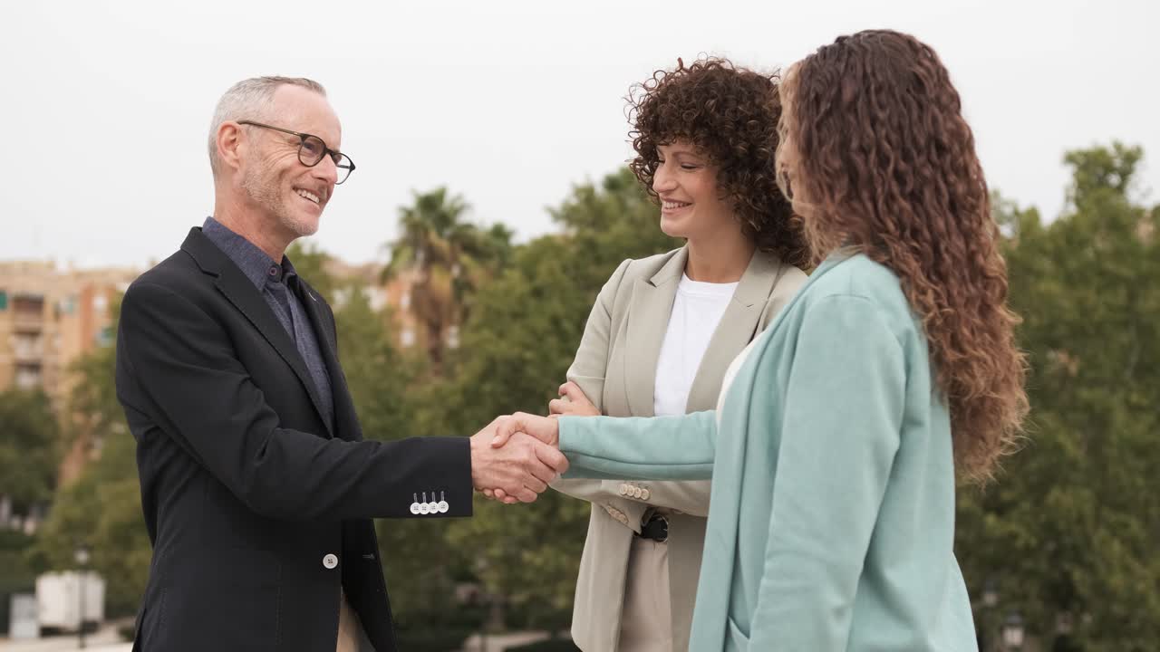 Happy business partners shaking hands in city