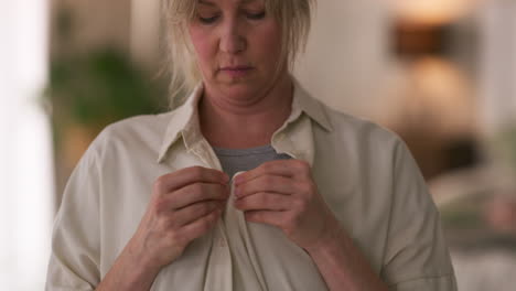 woman buttoning her shirt
