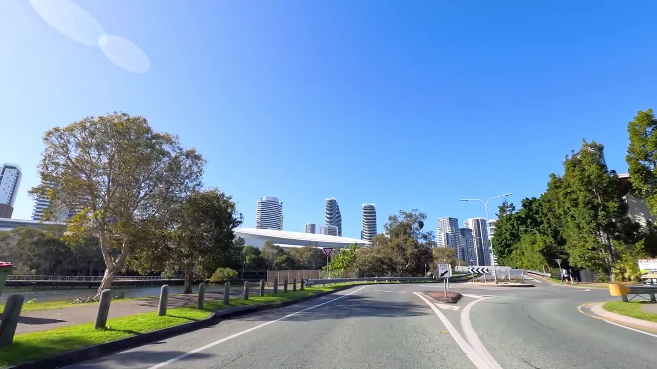 Perspective de conduite à la première personne le long d'une route bordée d'arbres sous un ciel bleu clair