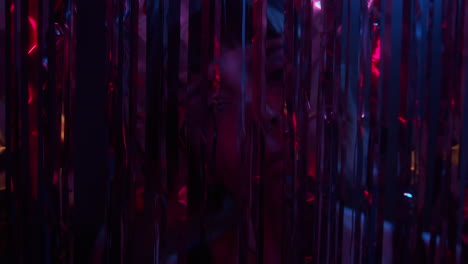 a young woman dances behind the glittering curtain