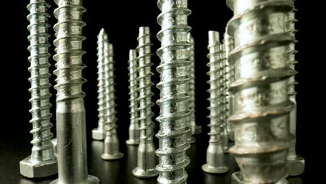 close-up of metal screws standing on a black background