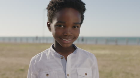 close up portrait of cute african american boy smiling cheerful looking at camera happy enjoying sunny day at seaside park