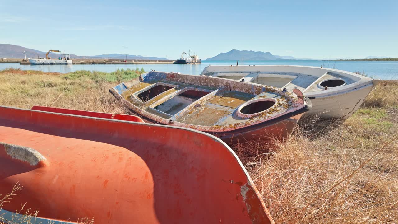 Abandoned Greek fishing boats neglected on silted grassy beach