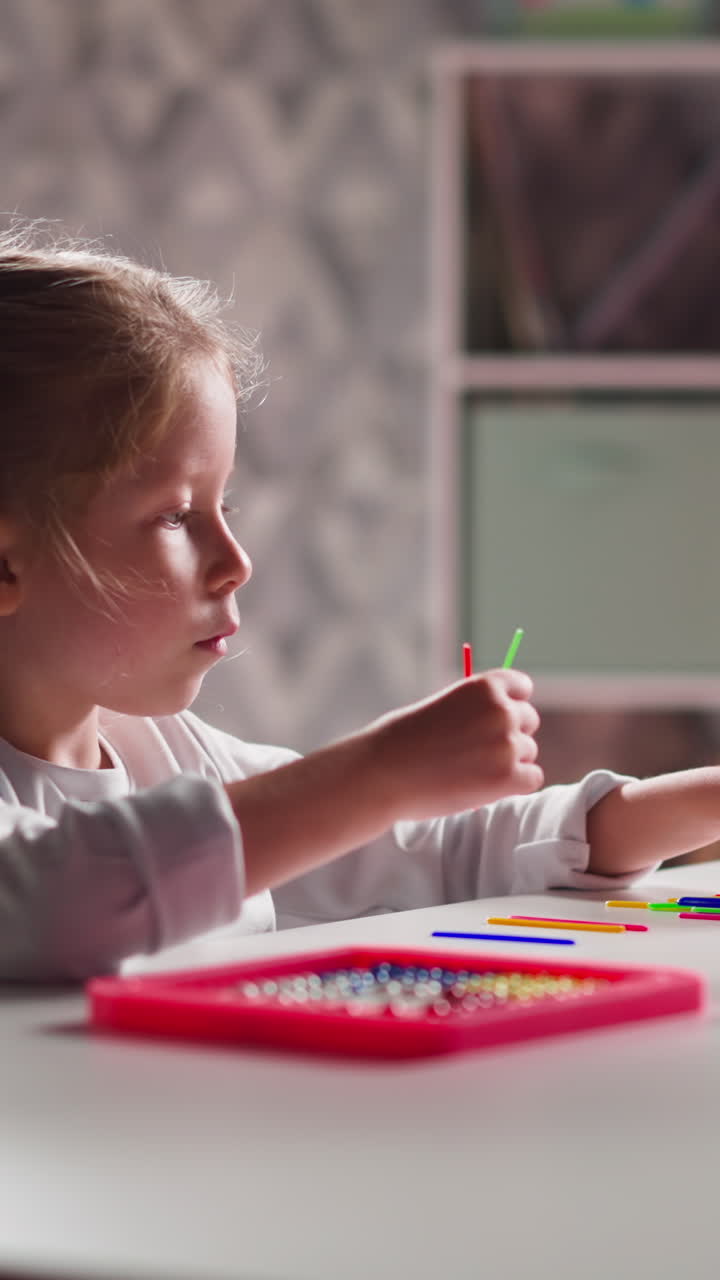 Interested blonde little girl learns to count with small colorful ...