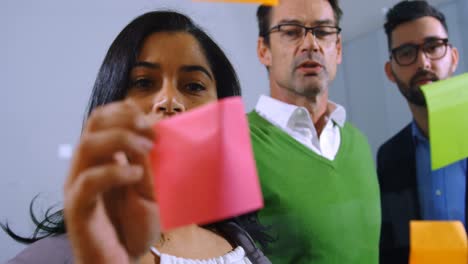 executives discussing over sticky note on glass wall in office 4k