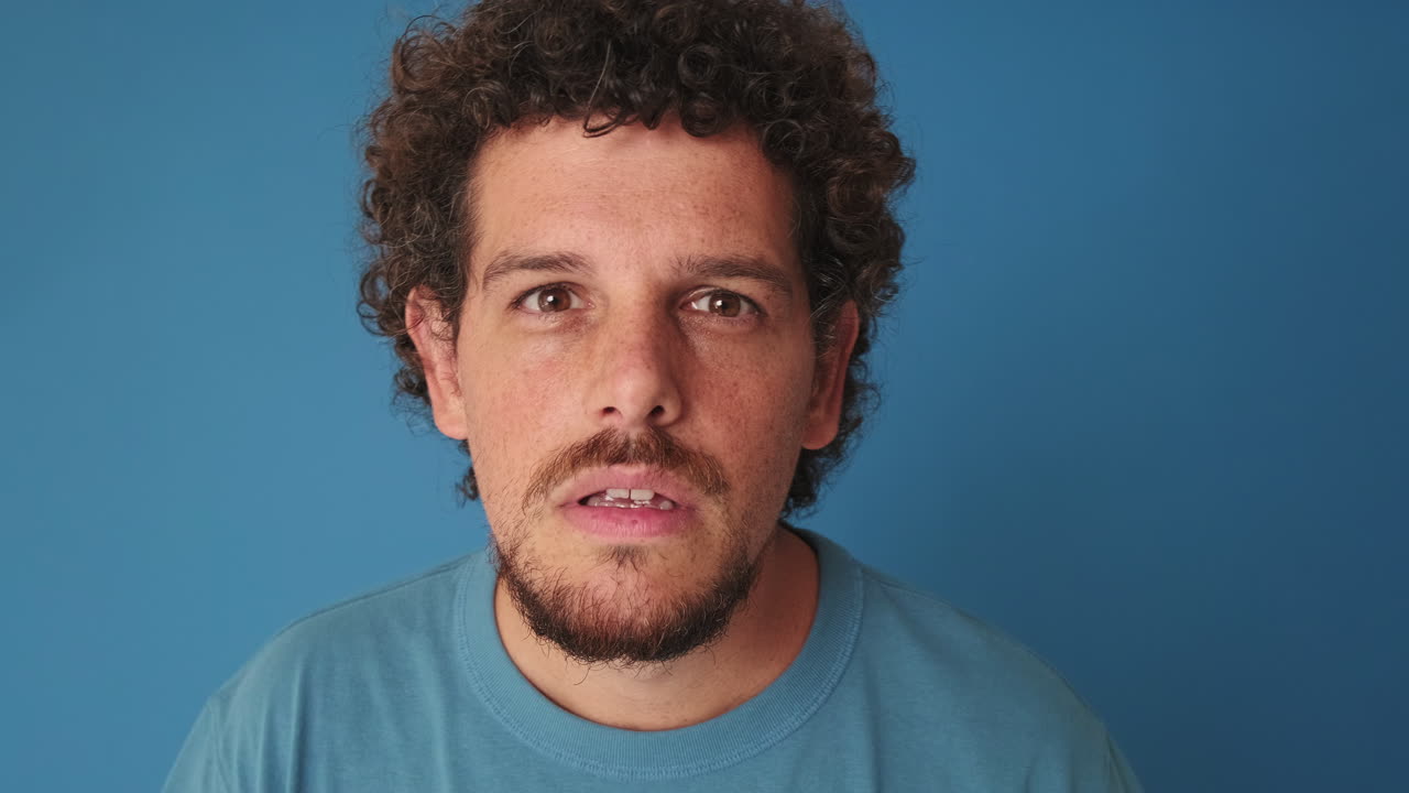 Mann mit verwirrtem und überraschtem Gesichtsausdruck auf blauem Hintergrund