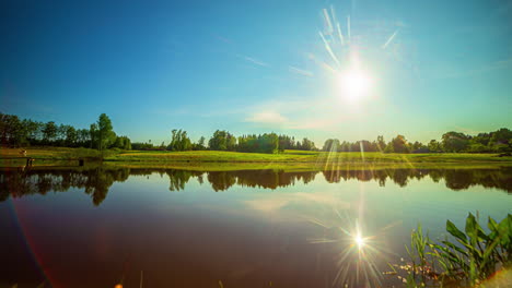 sun setting over beautiful farm lake, blue summer sky, golden summer sun, rural farm, static, timelapse