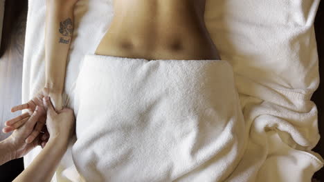 Top-view-of-patient-getting-hand-massage,-body-covered-in-white-towel