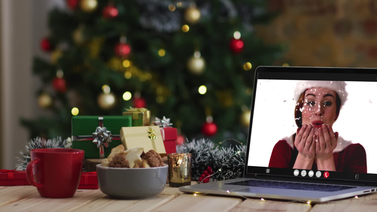 feliz mujer caucásica en disfraz de santa en videollamada en computadora portátil, con decoraciones de navidad y árbol
