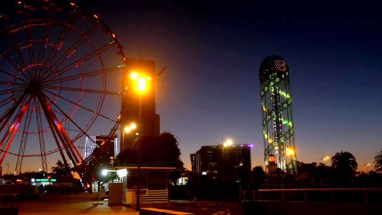 Panoramic view Statue of Ali and Nino on a background Ferris wheel at night on the embankment of Batumi, Georgia