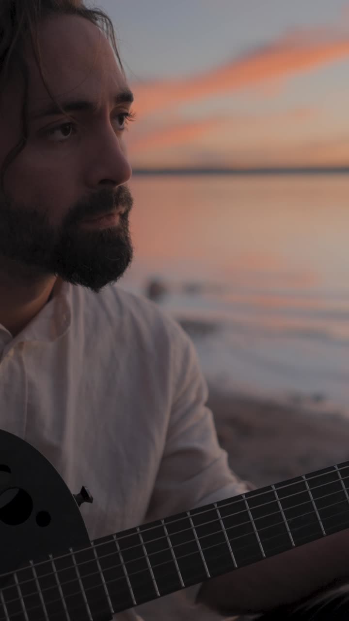 Man Playing Guitar at Sunset by the Lake