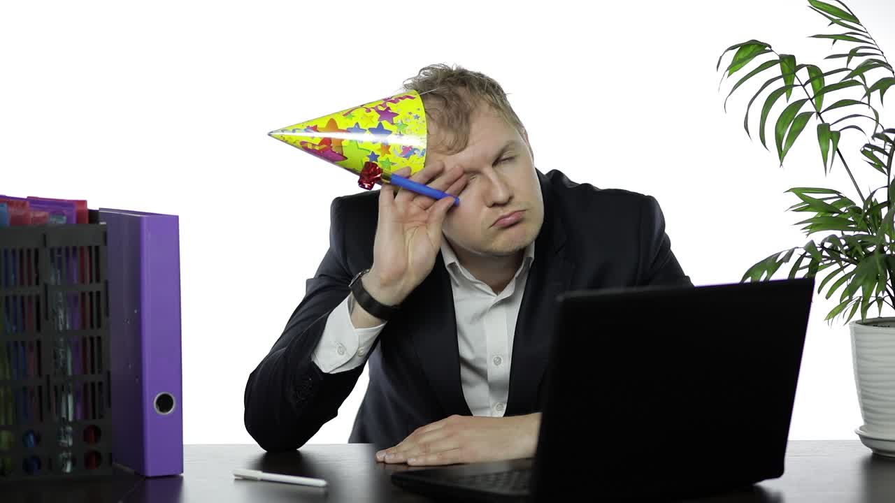 bebió un joven empresario somnoliento en una gorra festiva soplando un silbato. resaca