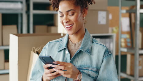 woman using phone in warehouse surrounded by boxes