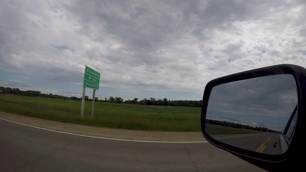 Driving in the Canadian prairies down the highway looking out the drivers side.