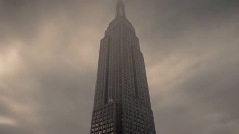 the iconic empire state building shrouded in mist against a cloudy sky