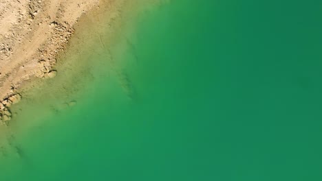 Zenithal-view-of-coastline-with-colorful-water-and-arid-terrain-textures