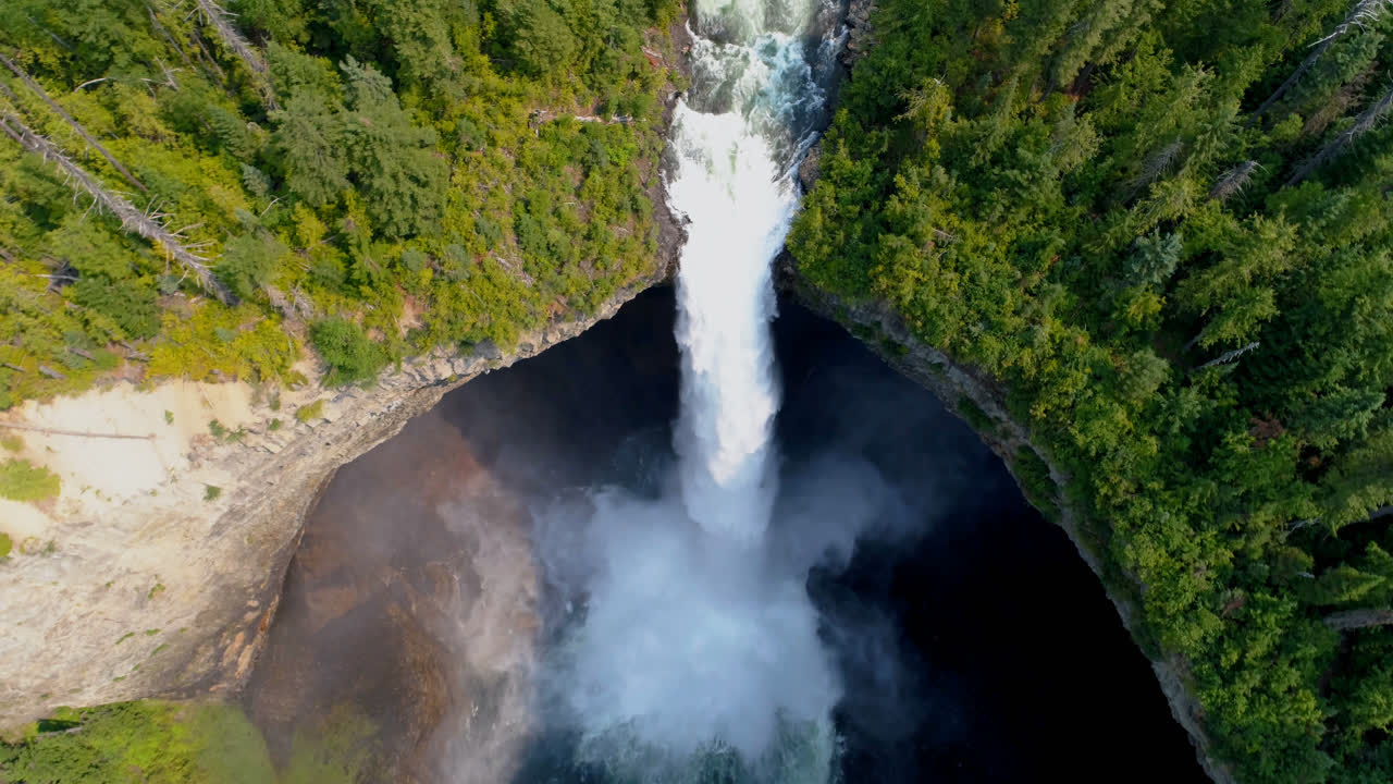 hermosa caída de agua a través del acantilado del bosque en un día soleado 4k