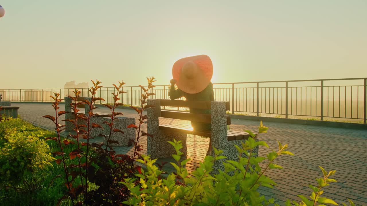 Woman sitting on a bench at sunrise in a park