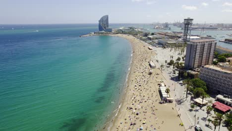 aerial view of crowded barceloneta beach and cityscape in barcelona, spain