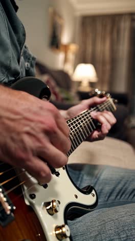 man playing electric guitar at home