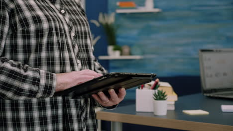 Close-up-of-old-woman-employee-texting-on-tablet