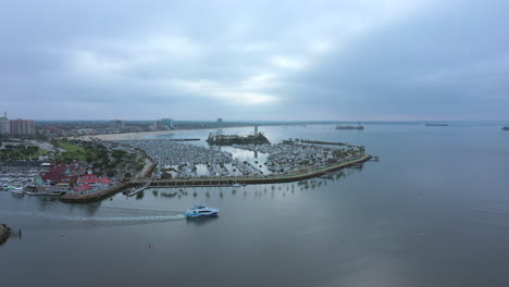 a yacht leaves the long beach, california harbor for the open waters of the pacific ocean on an overcast morning - aerial view in slow motion