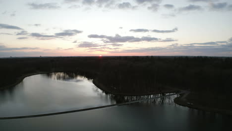 Puente-De-Bicicletas-Sobre-Estanque-De-Agua-Durante-La-Puesta-De-Sol,-Vista-Aérea-De-Drones