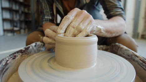 artisan potter shaping clay on a pottery wheel