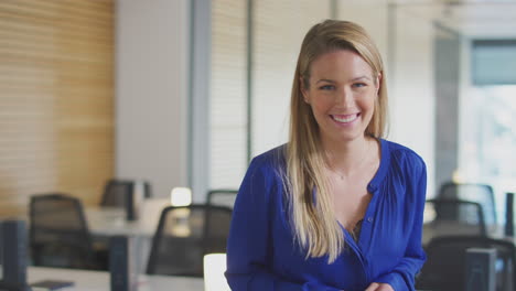 portrait of smiling young businesswoman standing in modern open plan office