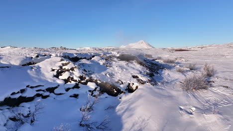 Steam-is-seen-from-a-volcano-in-Lake-Myvatan,-Iceland,-in-a-landscape-of-snow